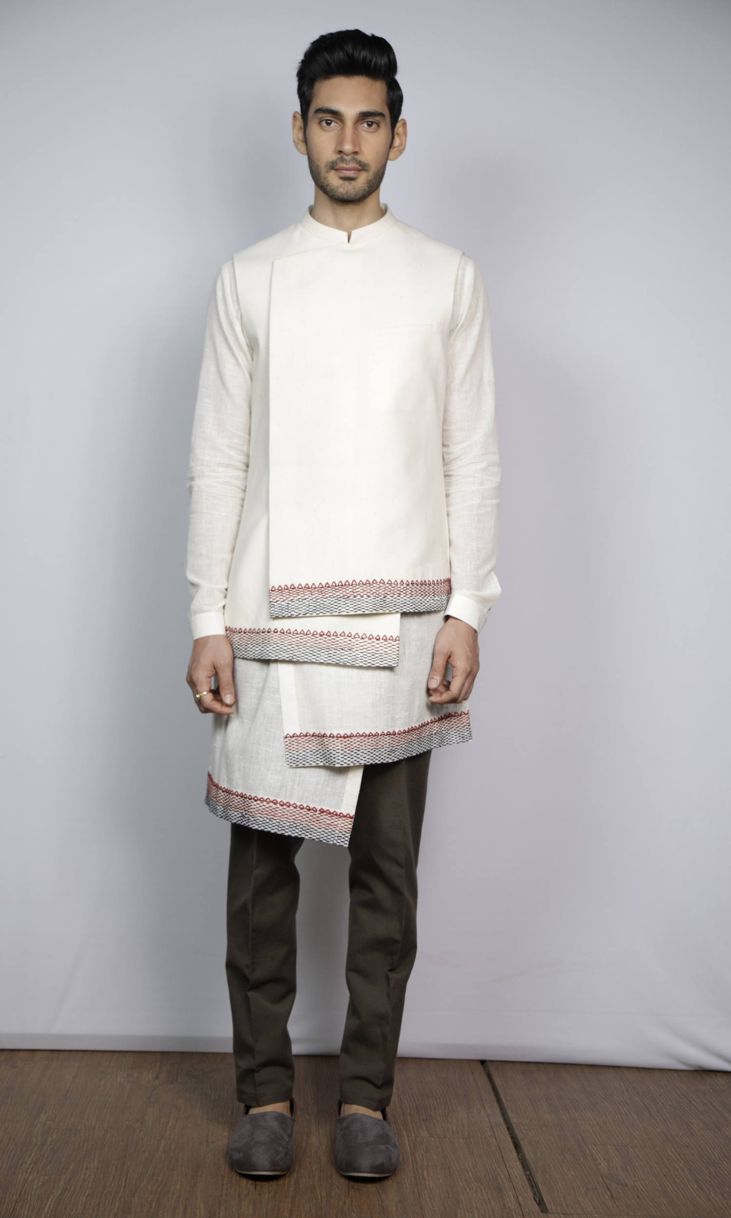 Off white asymmetrical bandi paired with off white asymmetrical kurta and dark grey fitted pants