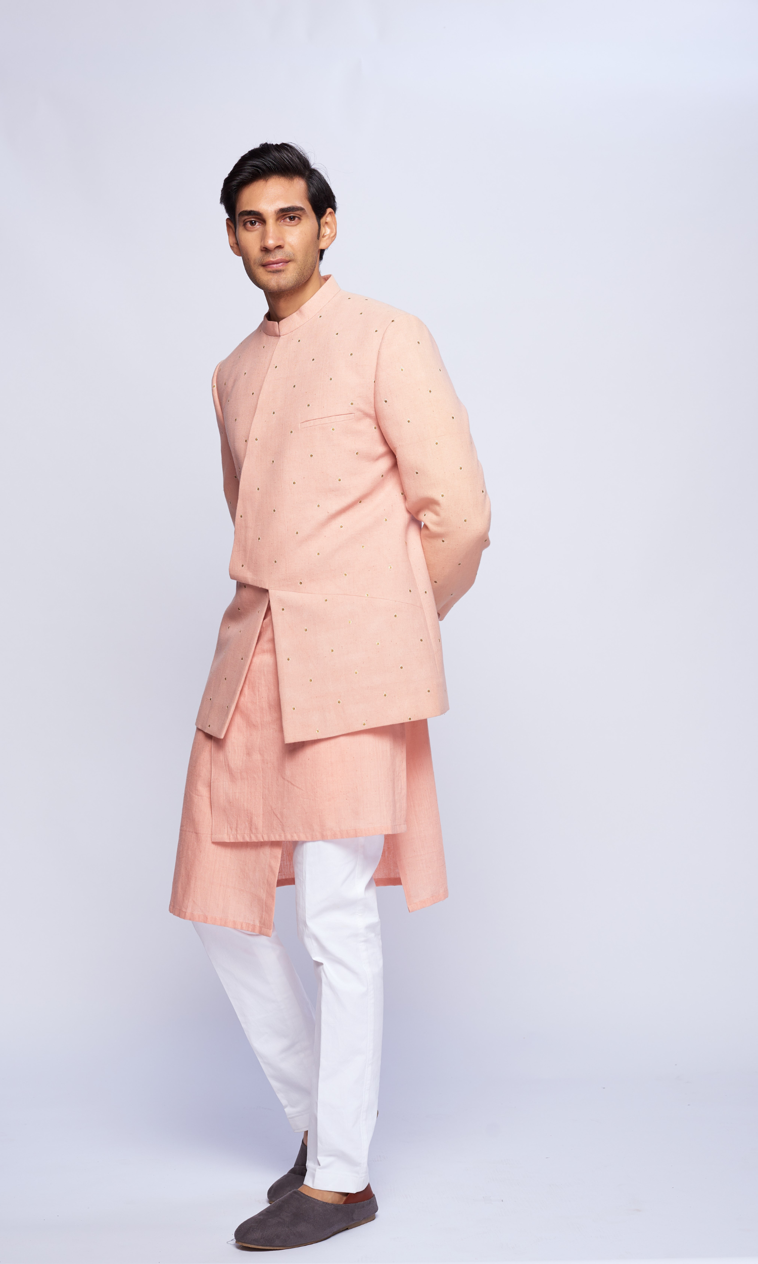 Dusky pink asymmetric yoke all over emb bandhgala paired with tonal asymmetrical kurta and fitted pants