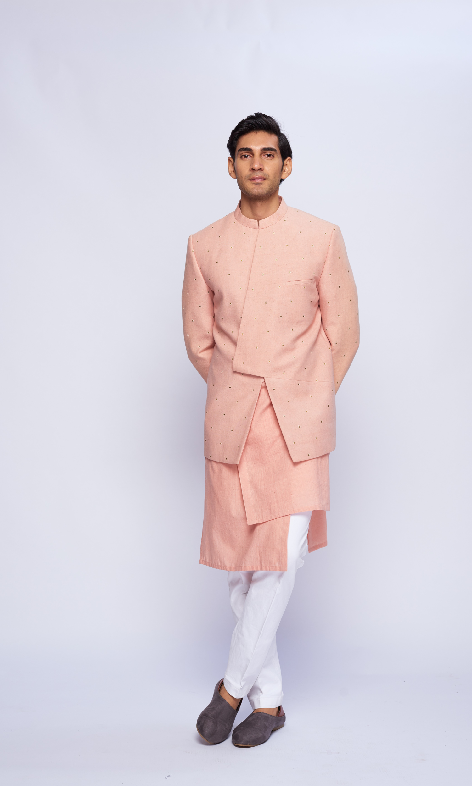 Dusky pink asymmetric yoke all over emb bandhgala paired with tonal asymmetrical kurta and fitted pants