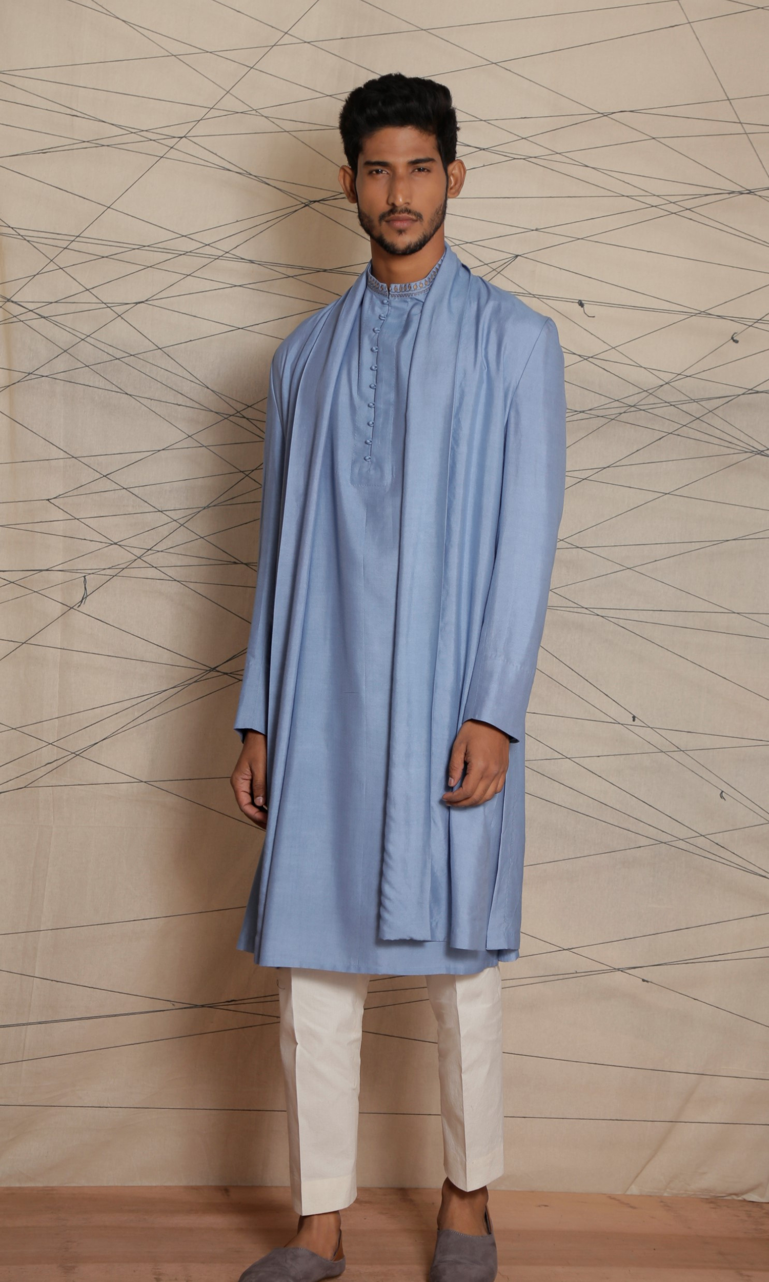 Powder blue deconstructed long cape paired with powder blue kurta with potli buttons and emb detail on collar and cuffs and fitted pants