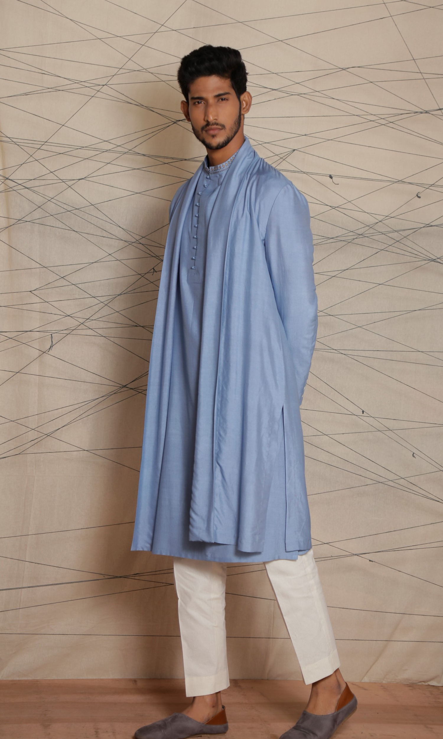 Powder blue deconstructed long cape paired with powder blue kurta with potli buttons and emb detail on collar and cuffs and fitted pants